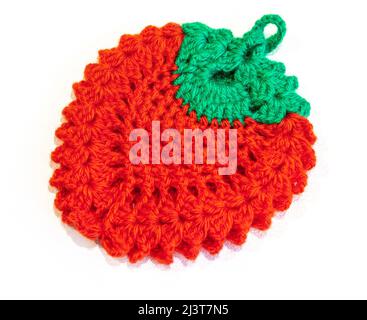 Knitted red-green rug in the form of a berry on a white background close-up. Stock Photo