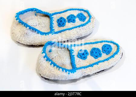 White knitted woolen slippers on a white background close-up. Stock Photo