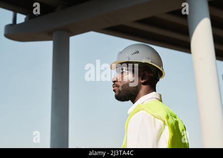 Professional engineer in hardhat in workwear standing at construction site Stock Photo