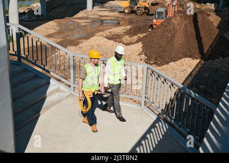 Two building contractors discussing project while standing at construction site, copy space Stock Photo