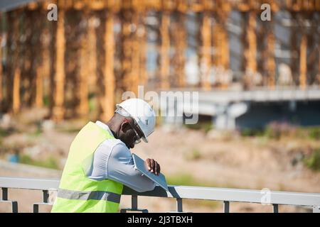 Head and shoulders portrait of bearded construction foreman speaking by walkie-talkie giving instructions to workers on site Stock Photo