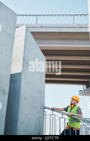 Wide angle shot of construction site with crew workers holding plans and discussing project, copy space Stock Photo