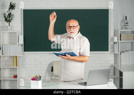 Senior teacher with books and chalkboard. Old smiling professor on ...