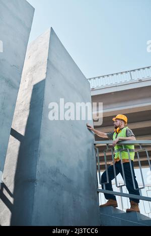 Wide angle shot of construction site with two workers discussing project by high rise building, copy space Stock Photo