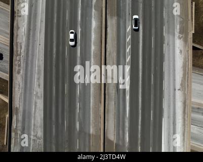 HOV lane logos are seen on a large highway interstate as two cars pass by. Stock Photo