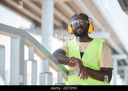 Portrait of young African-American man working at construction site and smiling at camera, copy space Stock Photo