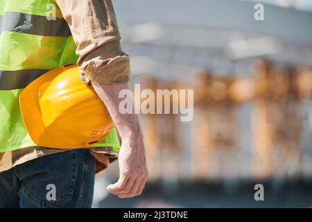 Close up portrait of male construction worker wearing hardhat and looking at camera at construction site, copy space Stock Photo