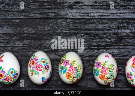 White Easter eggs made with decoupage technique with floral motifs on a black rustic background with large copy space Stock Photo