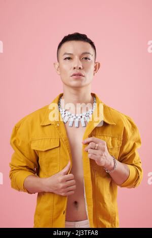 Portrait of stylish young man wearing mustard denim jacket and creative necklace Stock Photo
