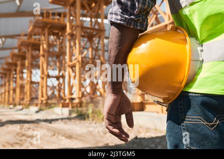 Building worker analyzing project plan and discussing blueprint while standing on construction site Stock Photo