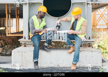 Two construction workers examining metal parts at construction site, copy space Stock Photo