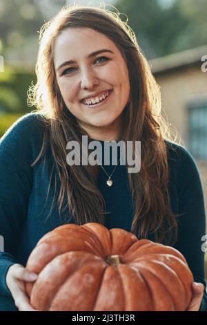 My favorite Holiday is coming. Portrait of a young woman holding a pumpkin outside. Stock Photo