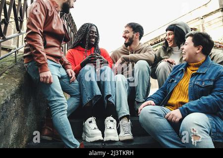 Classmate meeting of multi-cultural young students sitting on the stairway having fun chatting together Stock Photo