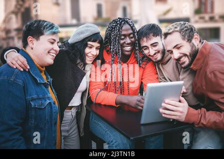 Three women and two men at cafe talking laughing and enjoying their time using digital tablet. Stock Photo