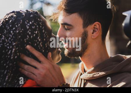 Engaged biracial couple of generation z young people kissing in the park - closeup shot Stock Photo