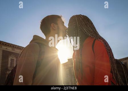 Multiracial couple of young people kissing outdoors traveling in the city center Stock Photo