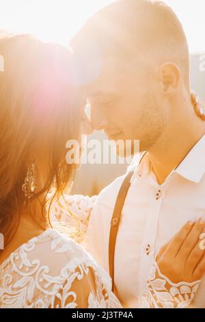 Stylish groom kissing gorgeous bride in sun light, perfect moment, boho wedding couple Stock Photo