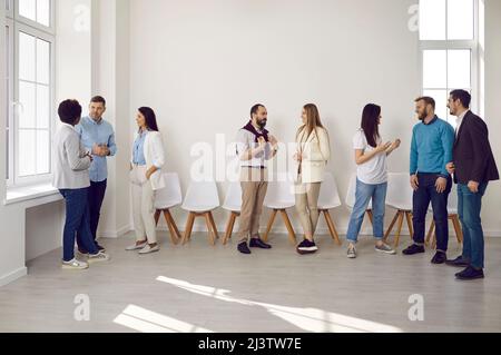 Different groups of colleagues communicate with each other during work break in coworking office. Stock Photo