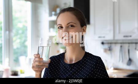 Woman holds glass of water, smiles looks at camera Stock Photo