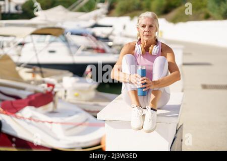Senior woman in fitness clothing taking a break during exercise. Stock Photo