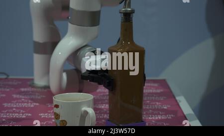Close-up of robotic hand pouring drink. HDR. Cybernetic hand trains to pour drinks. Creation and improvement of robotics and cyborgs Stock Photo