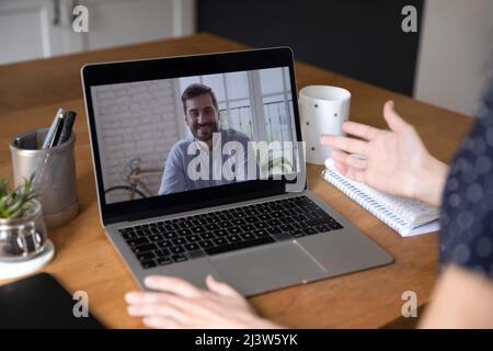 Woman have conversation via conference, laptop screen view over shoulder Stock Photo