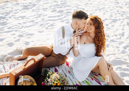 Picnic on the sand near the lake in summer. Beautiful young couple Stock Photo