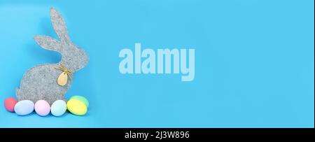 Easter, soft, gray hare and eggs are plain, multi-colored on a blue background.  Stock Photo