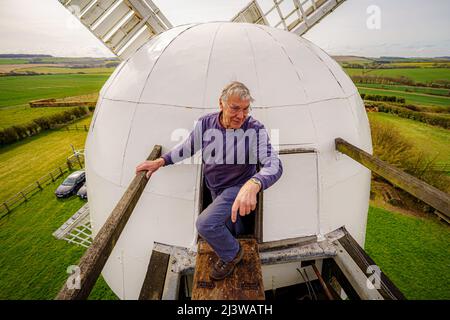 Volunteers exit the cap to check the fantail at Wilton windmill, Wiltshire, where members of the Wilton Windmill Society are helping to complete the annual Spring clean of the traditional tower mill with fantail, built in 1871 and operational for 100 years. Picture date: Sunday April 10, 2022. Stock Photo
