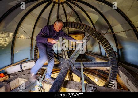 Volunteers clean and grease cogs inside Wilton windmill, Wiltshire, where members of the Wilton Windmill Society are helping to complete the annual Spring clean of the traditional tower mill with fantail, built in 1871 and operational for 100 years. Picture date: Sunday April 10, 2022. Stock Photo