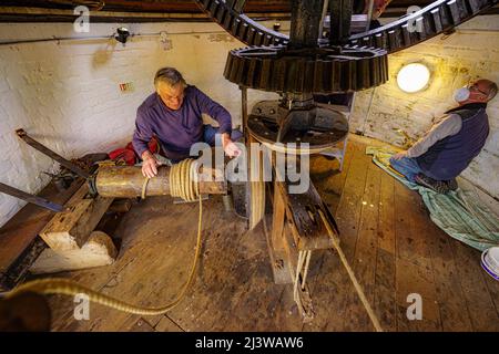 Volunteers clean walls and check ropes inside Wilton windmill, Wiltshire, where members of the Wilton Windmill Society are helping to complete the annual Spring clean of the traditional tower mill with fantail, built in 1871 and operational for 100 years. Picture date: Sunday April 10, 2022. Stock Photo