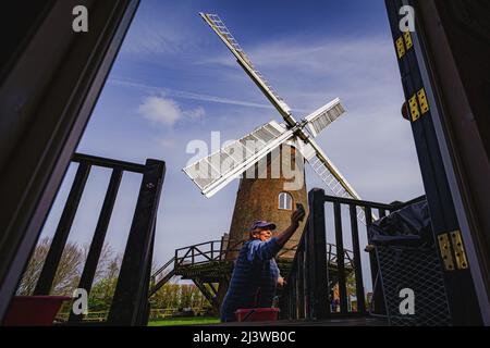 Volunteers clean woodwork on the shepherds hut at Wilton windmill, Wiltshire, where members of the Wilton Windmill Society are helping to complete the annual Spring clean of the traditional tower mill with fantail, built in 1871 and operational for 100 years. Picture date: Sunday April 10, 2022. Stock Photo