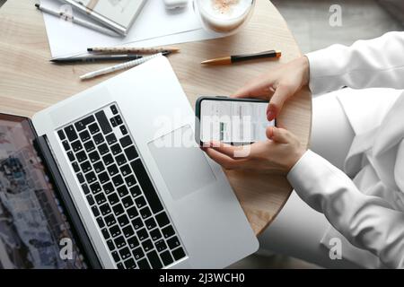 Closeup womans hands holding phone and working at laptop computer. Working at home. Online shopping concept. Stock Photo