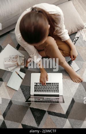 Closeup womans hands holding phone and working at laptop computer. Working at home Stock Photo