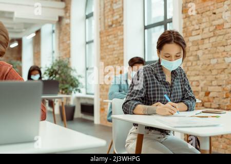 Students are taking notes from book for her study Stock Photo