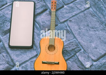 Phone with space for text, acoustic guitar on a cobbled grey blue background Stock Photo