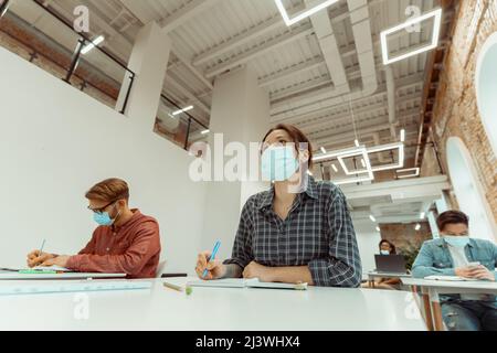 Caucasian woman attentively listening to teacher at university Stock Photo