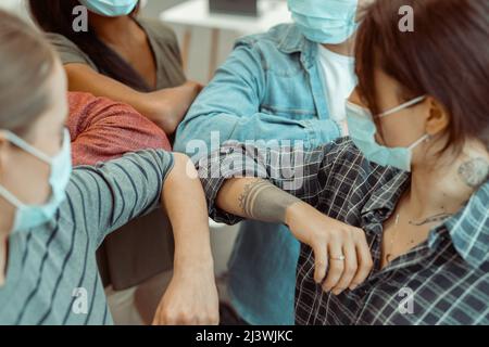 Students wearing face mask doing new social distancing greet with elbows Stock Photo