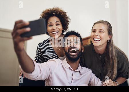 Big smiles from the top creative team. Shot of a group of businesspeople taking selfies together in an office. Stock Photo