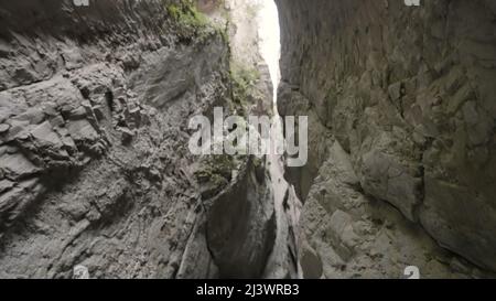 Geological formation with a very narrow passage. Action. Bottom view of the stone gorge with greenery. Stock Photo