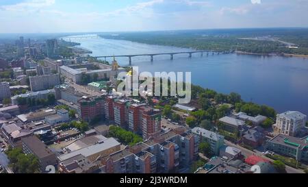 Aerial view of the city located in picturesque area on a summer day. Clip. A church with the golden dome, a river and city houses with the forested Stock Photo