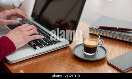 Woman work with a computer, female hands on laptop keyboard, close up view. Modern creative office workspace, wooden table, home office. Stock Photo