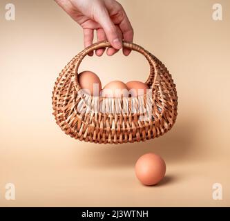 Hand holding basket with farm eggs. Easter celebration tradition or organic food concept on beige background. High quality photo Stock Photo