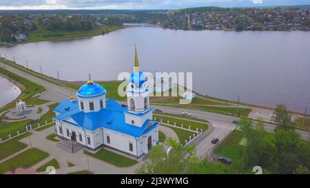 Aerial view of the city located in picturesque area on a summer day. Clip. A church with the blue roof, a pond and city houses far in the distance Stock Photo