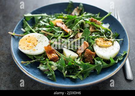 Dandelion salad with eggs and roasted bacon close up Stock Photo