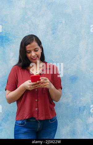 Latina woman checking her cell phone standing outdoors on the street Stock Photo