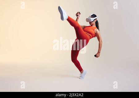 Active young woman working out using 3D technology. Sporty young woman exploring a virtual reality fitness game. Athletic young woman wearing virtual Stock Photo