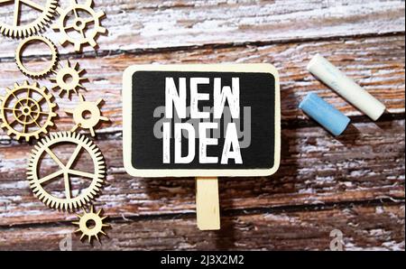Business concept. Notebook with text new idea sheet of white paper for notes, calculator, magnifying glass, woden blocks, on the charts background. Stock Photo
