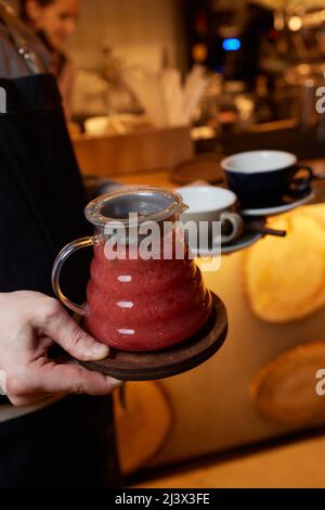 Herbal tea winter tea in french press served by a waitress ,Winter tea in french press served with cookie also some herb beside and a jar of honey Stock Photo