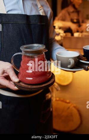 Herbal tea winter tea in french press served by a waitress ,Winter tea in french press served with cookie also some herb beside and a jar of honey Stock Photo